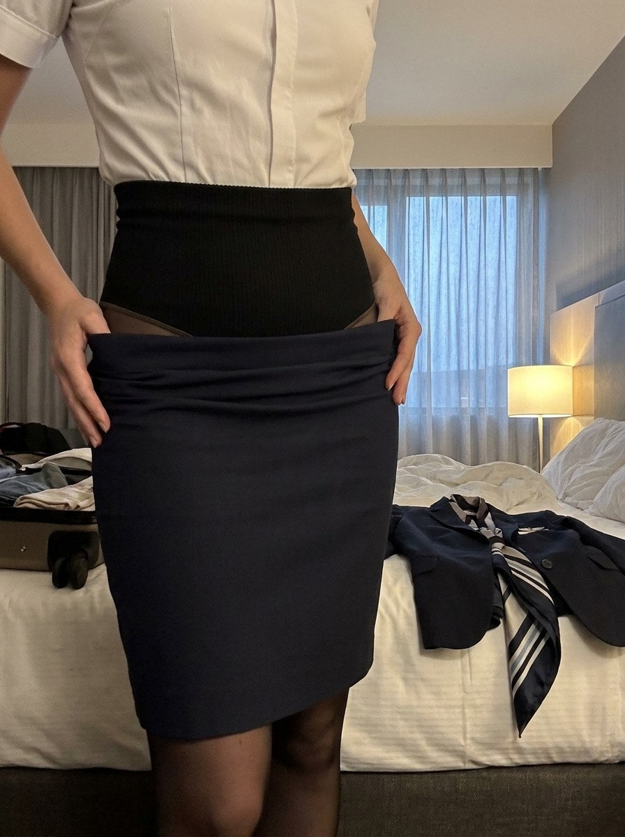 Flight attendant pulling her uniform skirt down to show the wide compression waistband of her tights underneath