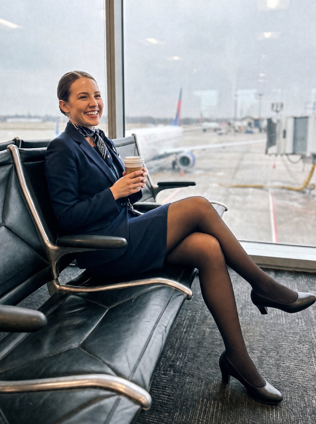Flight attendant sitting at the gate with a coffee